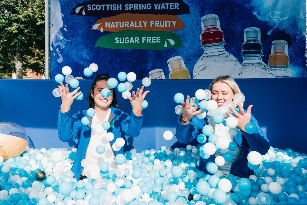 two girls in ball pit throwing balls in air