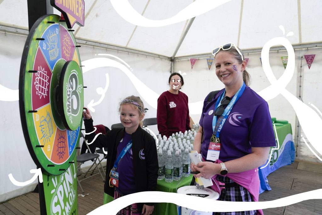 macb staff members standing in front of a spin the wheel game