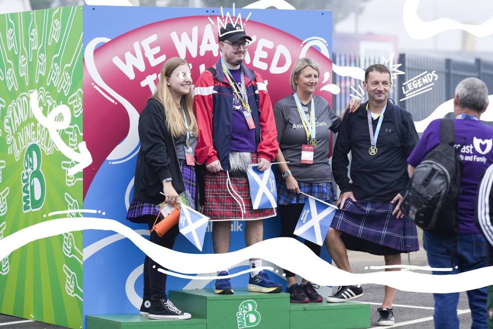The winners of the Kiltwalk in front of a macb banner and standing on a macb podium